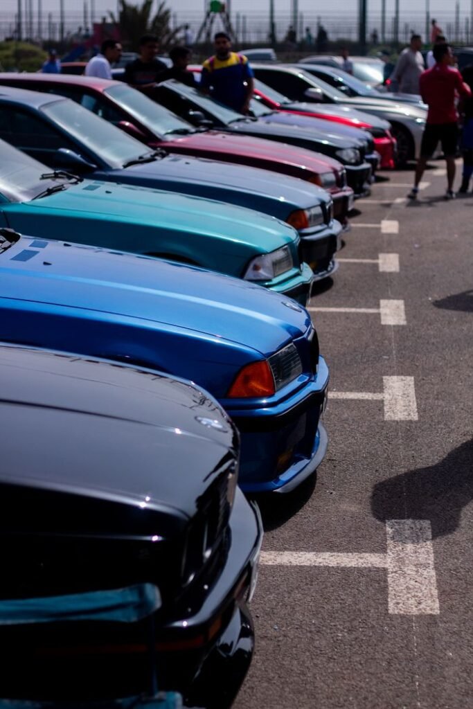 A colorful lineup of classic BMW cars parked at an outdoor car show, showcasing vintage automotive style.