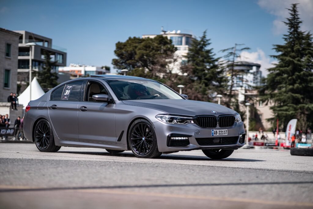 Gray BMW Series 5 featured at an outdoor car show, showcasing luxury automotive design.